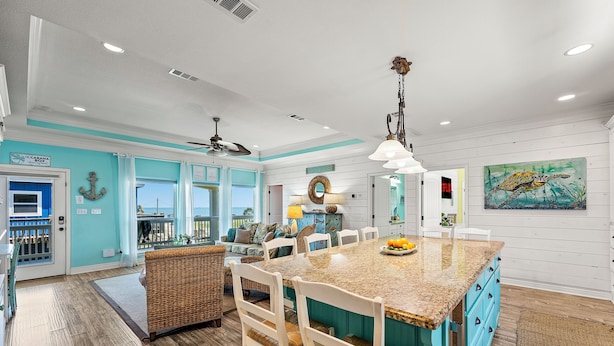 A spacious kitchen with a large island, white cabinetry, and a view to the outside. - Beach Retreat | Views, Bar, BBQ, Arcade, Games, Fenced Yard, Deck, Steps to Sand (Port Bolivar)