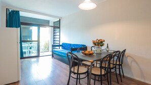 A dining area with a table, chairs, a sofa, and a hanging light fixture. - Cosy apartment for 4 people with WIFI, pool, A/C, TV and patio (Bibbona)