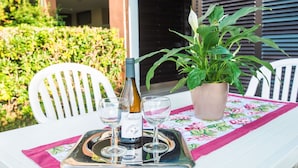A table set outdoors with a bottle of wine, two glasses, and a tray. - Cosy apartment for 4 people with WIFI, pool, A/C, TV and patio (Bibbona)