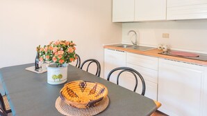 A small kitchen with white cabinets, a sink, and a countertop. There is a vase with flowers on the table. - Cosy apartment for 4 people with WIFI, pool, A/C, TV and patio (Bibbona)