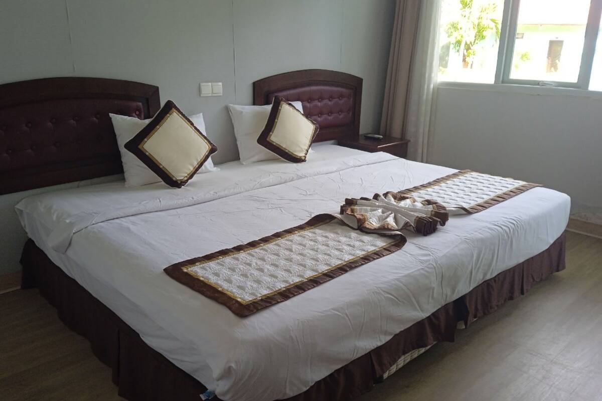 Un lit double avec une tête de lit en bois, une literie blanche et des coussins décoratifs.