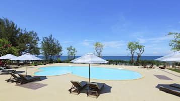 Una piscina al aire libre, sombrillas, sillones reclinables de piscina