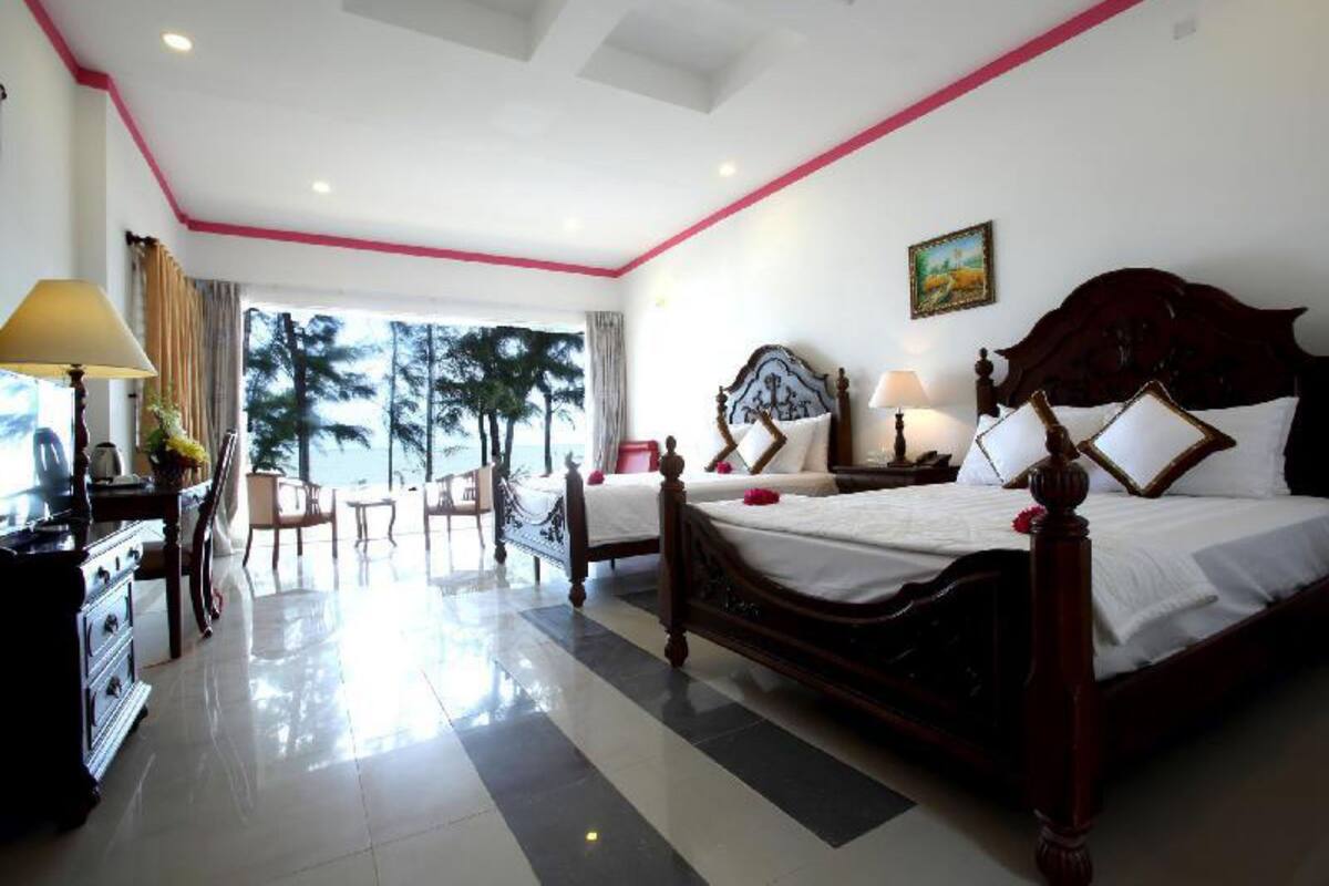 Une chambre d’hôtel avec un grand lit, un bureau et une vue sur les palmiers.