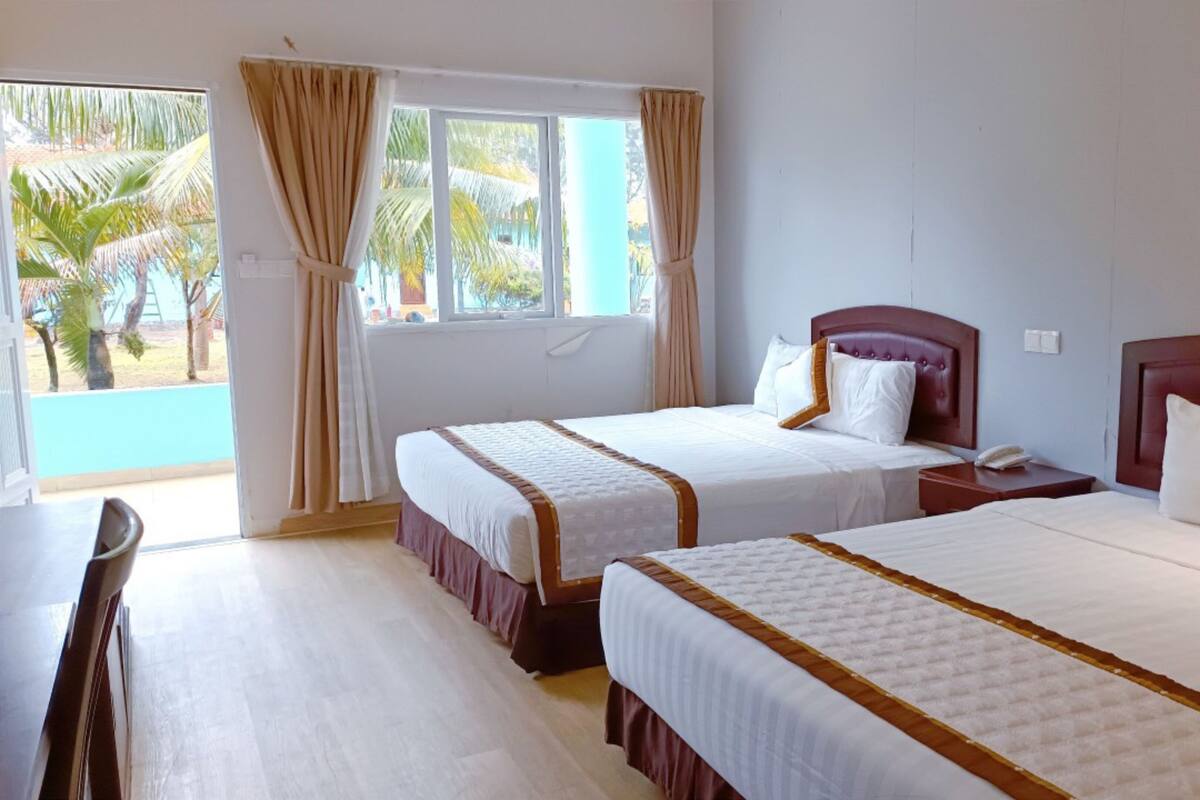 Une chambre d’hôtel avec deux lits, un bureau et une fenêtre avec des rideaux.