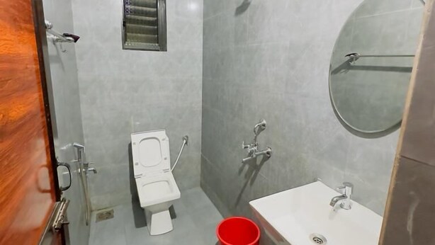 Une petite salle de bain comprenant des toilettes, un lavabo, une douche et une petite fenêtre.