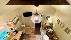 A compact living space with a kitchen, dining area, and seating area, featuring a unique ceiling structure and a decorative hanging light. - Charming Cottage Retreat in Lewistown – Sleeps 4 (Lewistown)