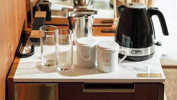A kitchen counter with a DeLonghi electric kettle, two glass tumblers, and two white canisters with the Candeo Hotel logo.