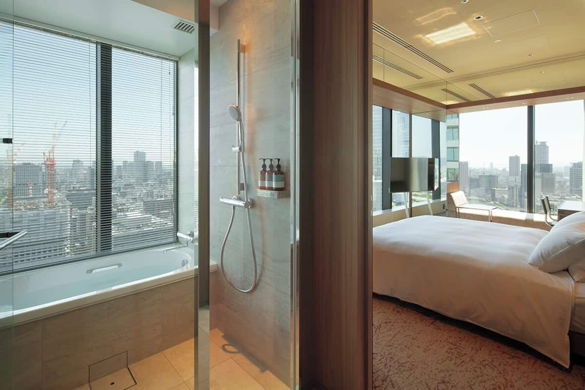 Une chambre moderne avec un grand lit, une douche en verre et une vue sur la ville.