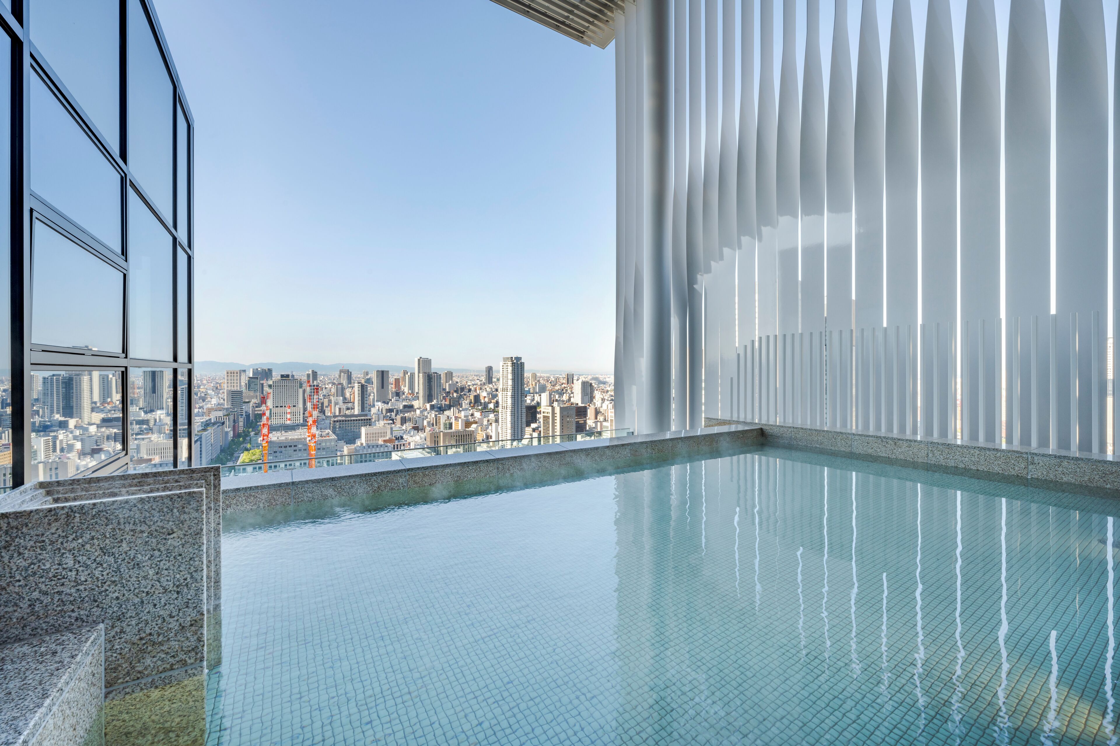 A modern indoor pool with a city view, large windows, and a contemporary design.