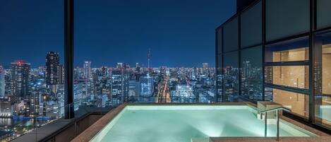 A rooftop infinity pool with a cityscape view, glass railings, and a modern architectural design.