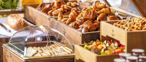 A breakfast buffet with various pastries, sandwiches, and fruit.