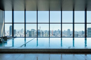 Piscina interior moderna con vistas a la ciudad a través de amplios ventanales.