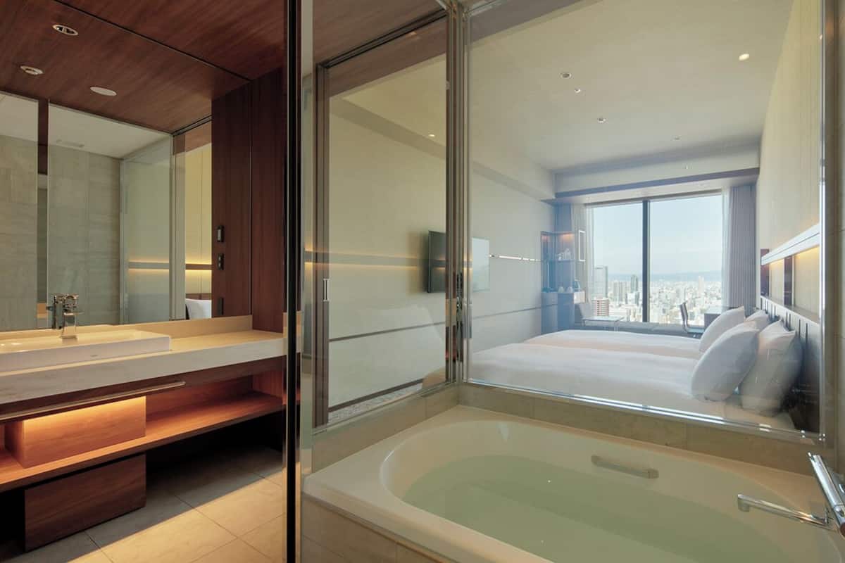 Une salle de bain moderne avec un grand miroir, une baignoire et une vue sur la ville.