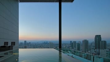 Una piscina infinita en la azotea con vistas a la ciudad, barandilla de cristal y diseño arquitectónico moderno.