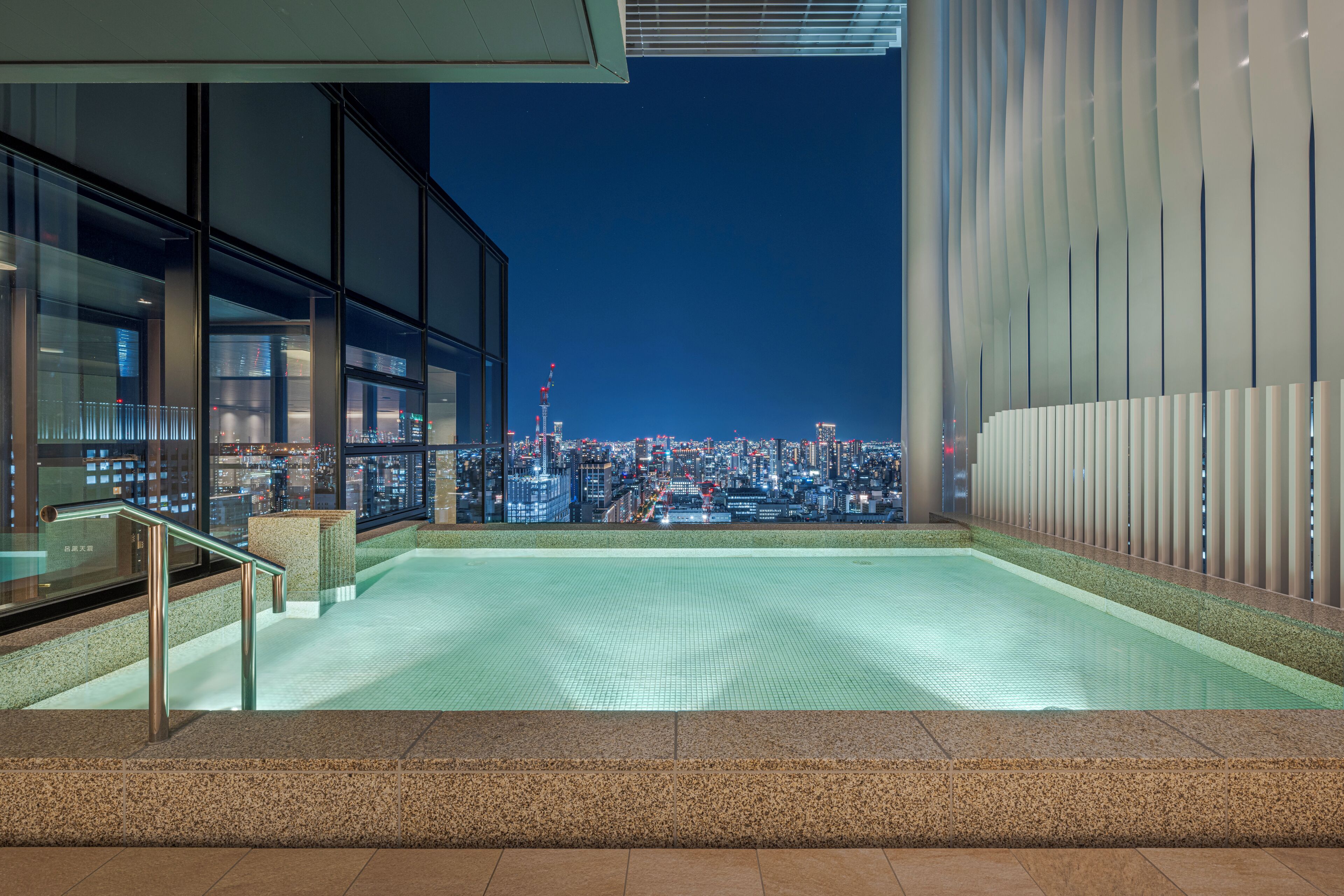 A rooftop pool with a cityscape view, glass railings, and a modern architectural design.