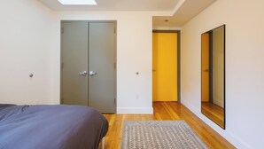 Un dormitorio con cama, armario, espejo y tragaluz.