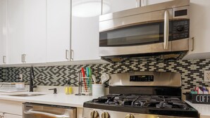 Una cocina moderna con electrodomésticos de acero inoxidable, armarios blancos y salpicadero a cuadros.