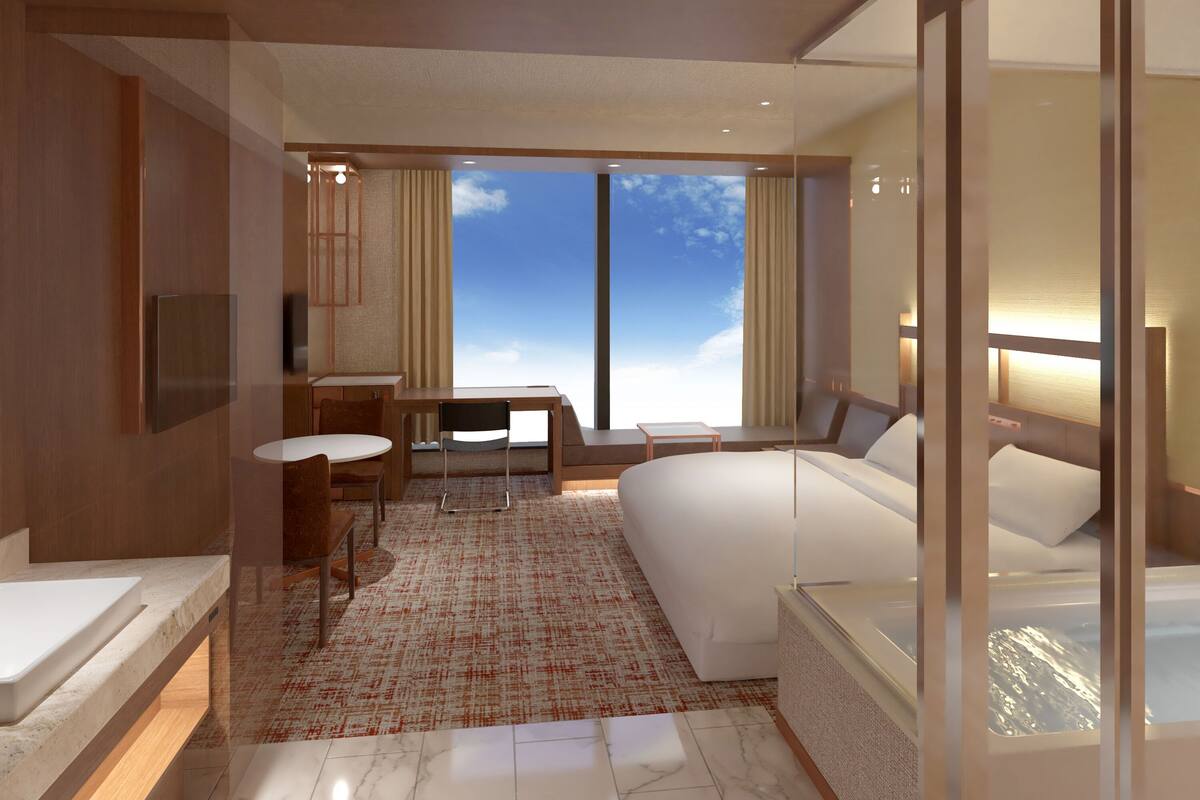 Een moderne hotelkamer met een groot bed, een bureau, een stoel, een klein tafeltje en een televisie.