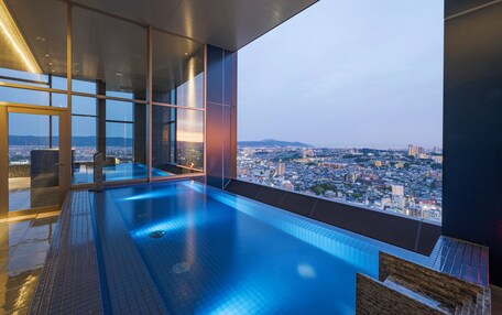 A modern infinity pool with a city view, glass walls, and a sleek design.