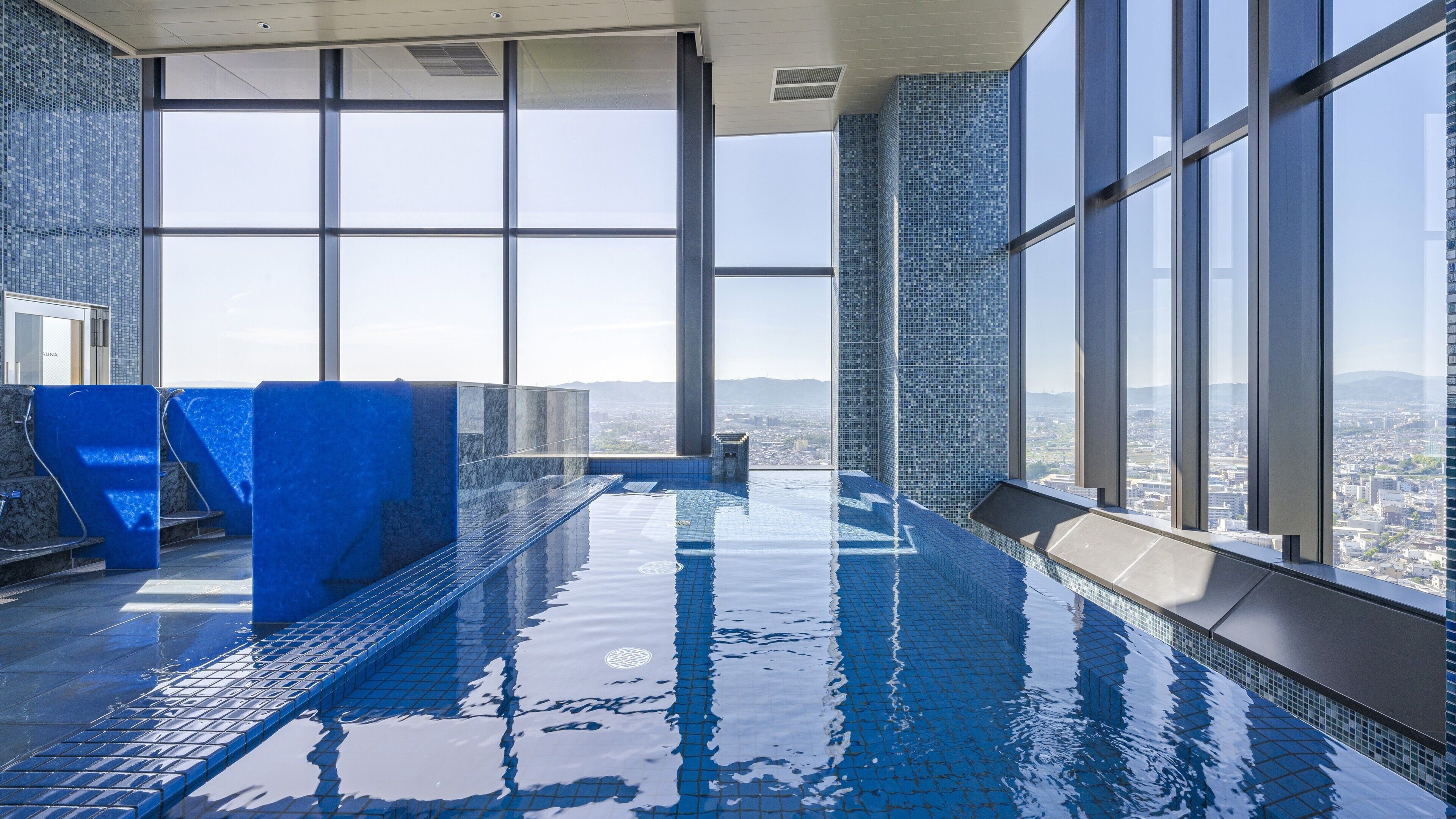 Ein Innenpool mit großen Fenstern und Blick auf die Stadt.