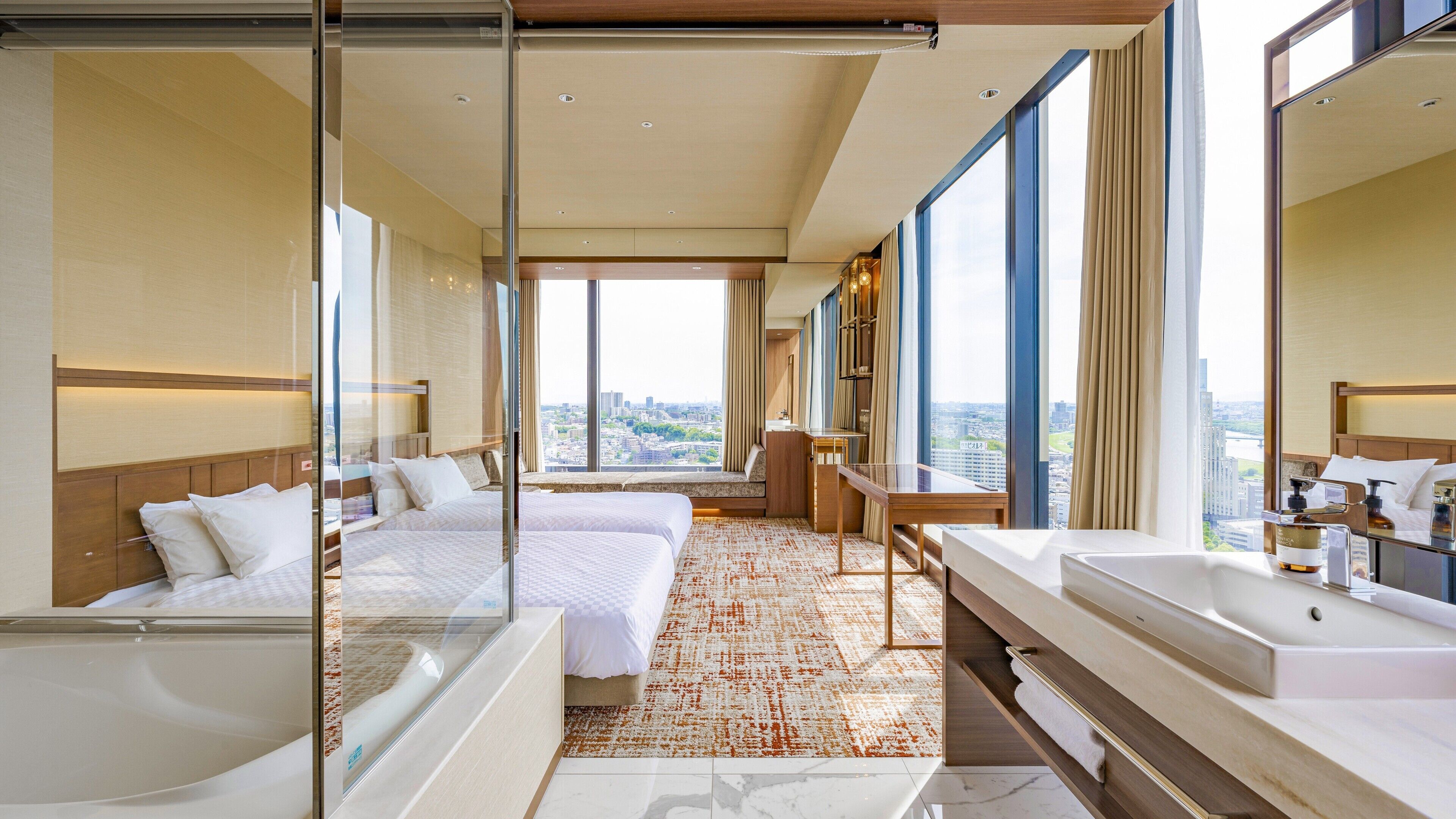 Ein Hotelzimmer mit einem großen Bett, einem kleineren Bett, einem Badezimmer mit Badewanne und Blick auf die Stadt.