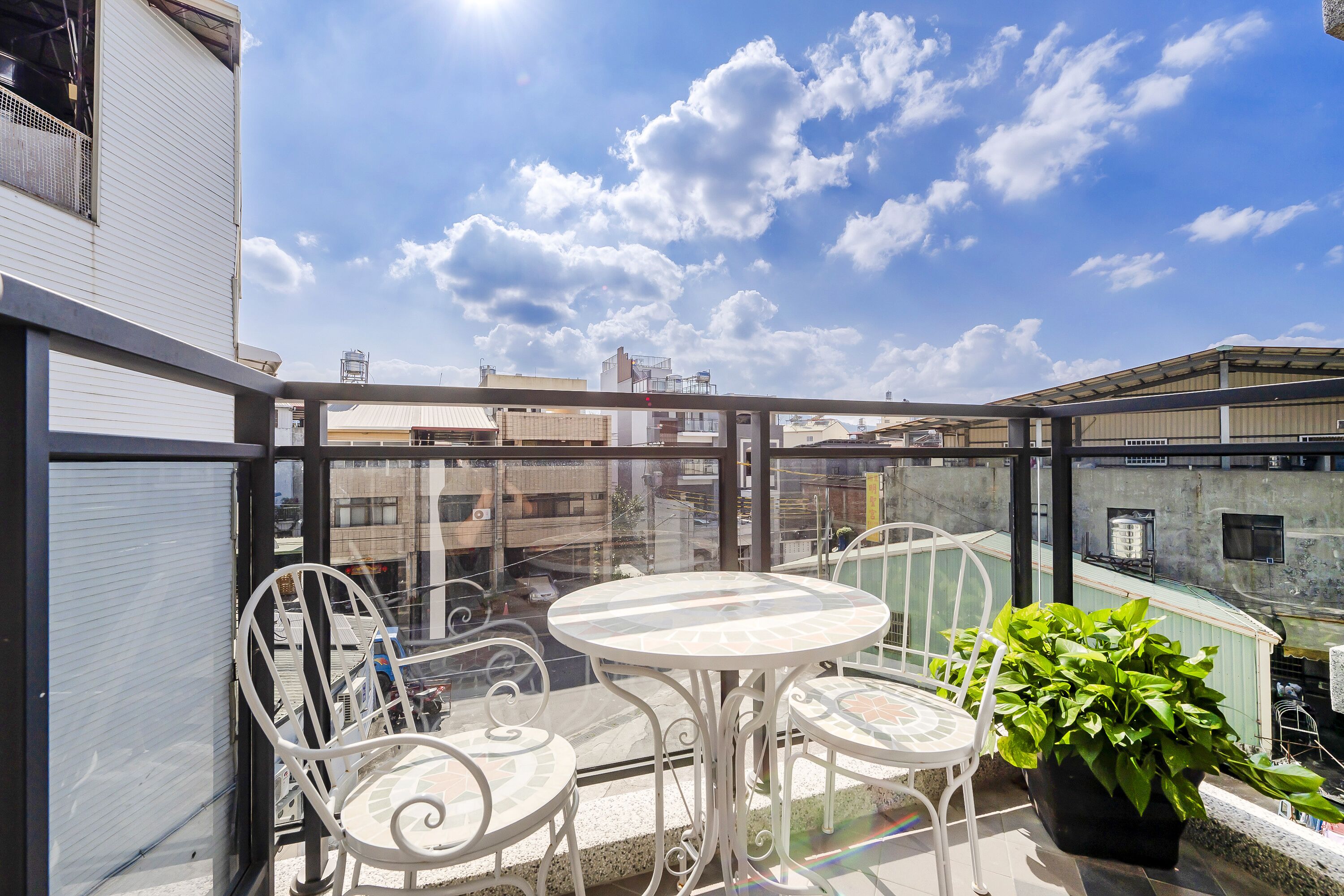 A balcony with a round table and chairs, a potted plant, and a view of the cityscape.