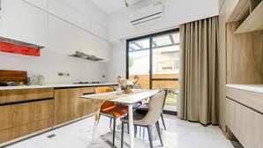 Eine moderne Küche mit Essbereich, ausgestattet mit einem großen Fenster mit Vorhängen, einem eingebauten Backofen und einem Holzschrank.