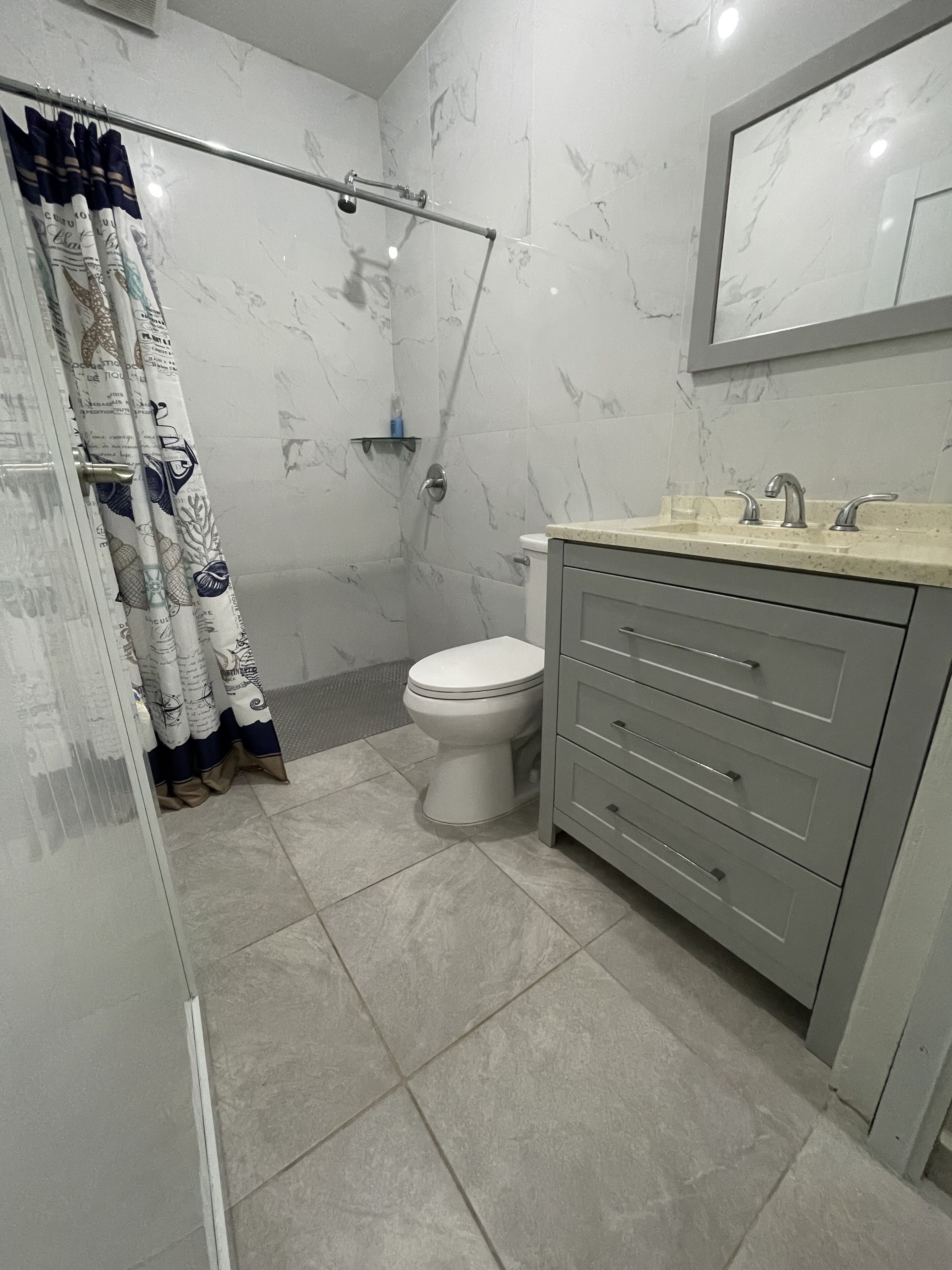A bathroom with a shower, toilet, and vanity with drawers.