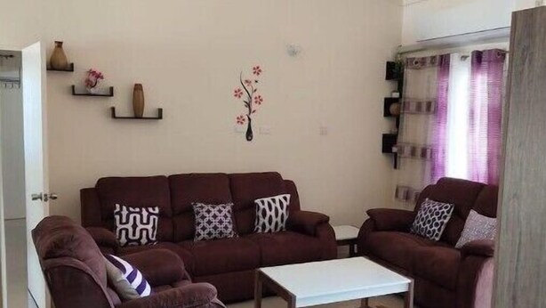 Ein Wohnzimmer mit braunen Sofas, einem weißen Couchtisch und einem Deckenventilator.