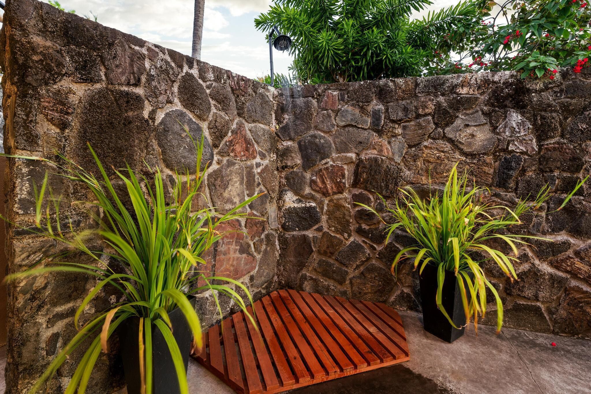 Un muro de piedra con un banco de madera y plantas en macetas.