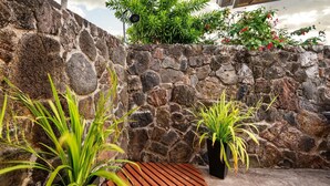 A stone wall with potted plants and a wooden bench. - Luxurious Makai Villa with Pool and Ocean Views (Kailua Kona)