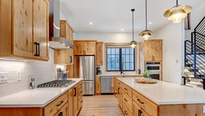 A modern kitchen with wooden cabinets, stainless steel appliances, and pendant lighting.