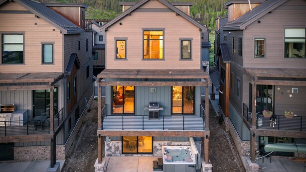 A modern residential building with a central patio featuring a hot tub, outdoor seating, and a covered area.