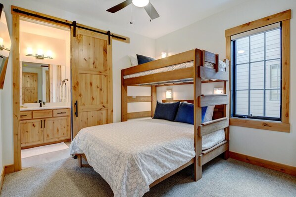 A bunk bed room with a sliding door closet, a large window, and a ceiling fan.
