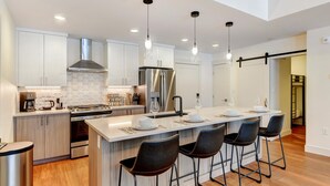 A modern kitchen with white cabinets, stainless steel appliances, and a central island with bar stools.