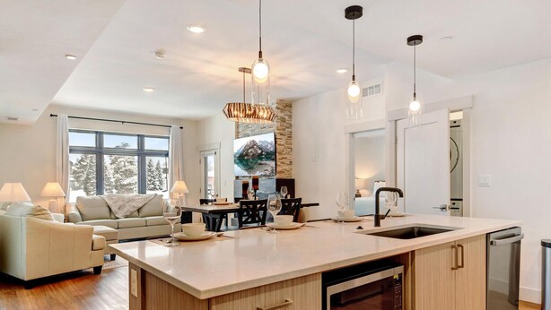 A modern kitchen with a large island, built-in oven, and a dining area with a view of the mountains.