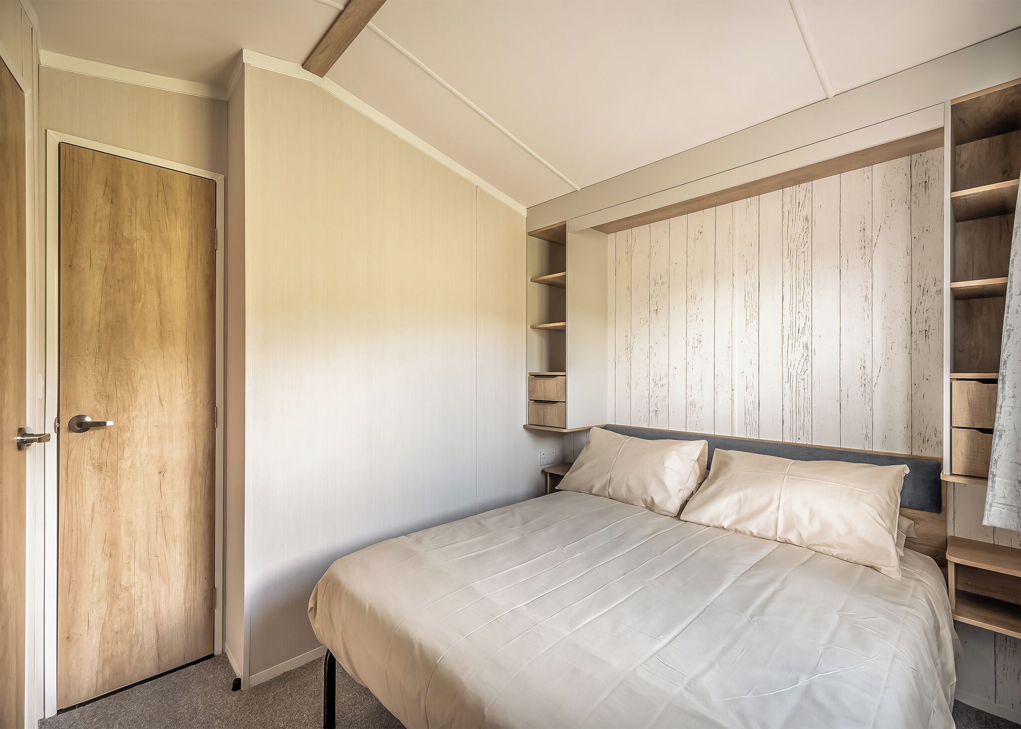 Een slaapkamer met een bed, een houten garderobe en een inbouwkast.
