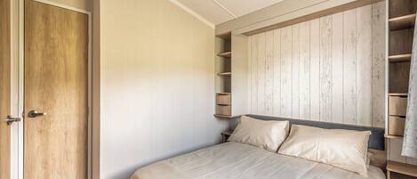 Een slaapkamer met een bed, een houten garderobe en een inbouwkast.