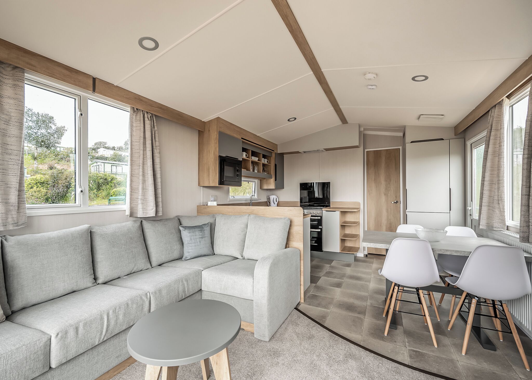 A modern RV interior with a sofa, dining table, and kitchen area.