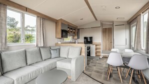 Ein modernes Wohnmobil-Interieur mit Sofa, Esstisch und Küchenzeile.