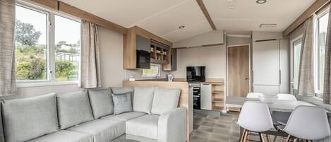 A modern RV interior with a sofa, dining table, and kitchen area.