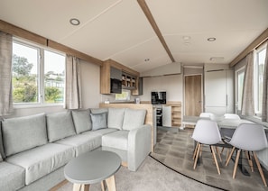 Un intérieur de camping-car moderne, comprenant un canapé, une table à manger et un coin cuisine.