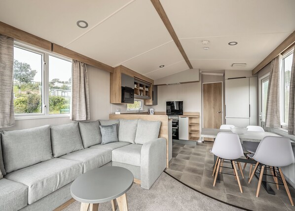 Un intérieur de camping-car moderne, comprenant un canapé, une table à manger et un coin cuisine.