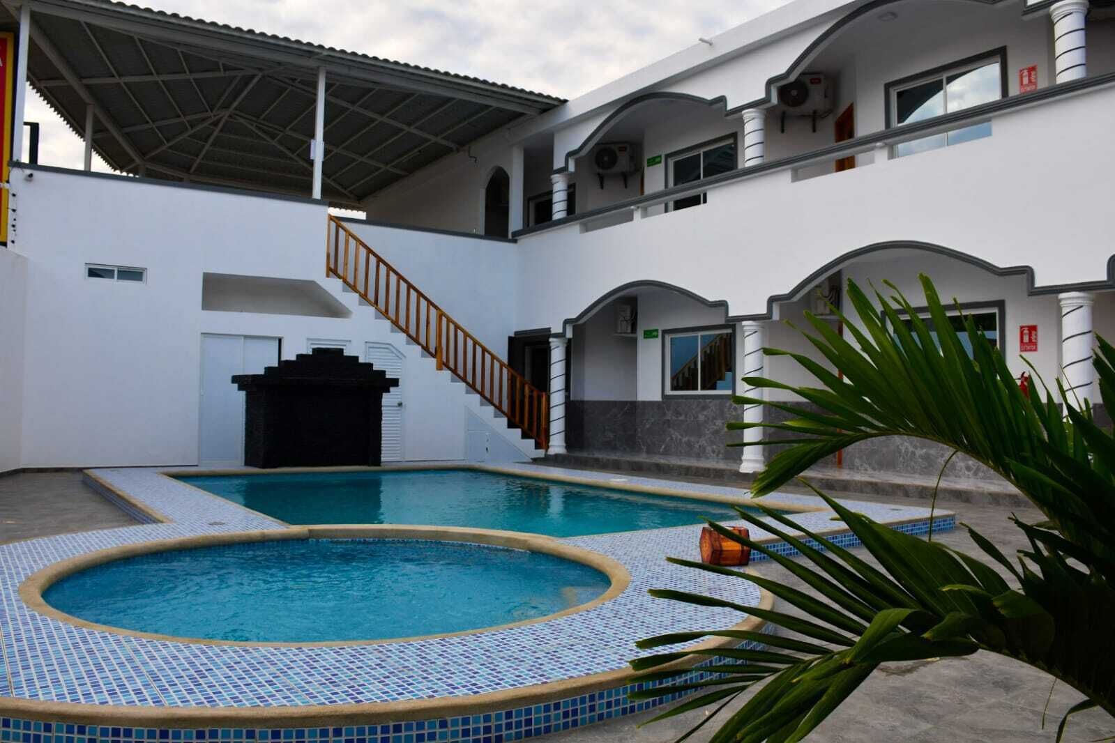 Piscina com deck revestido em azulejo, escadaria e área coberta com telhado.
