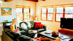 A living room with a sofa, a coffee table, a television, and a window with a view of the outdoors. - Entire home with privacy and views 10 mins to town 25mins to ski area  (El Prado)