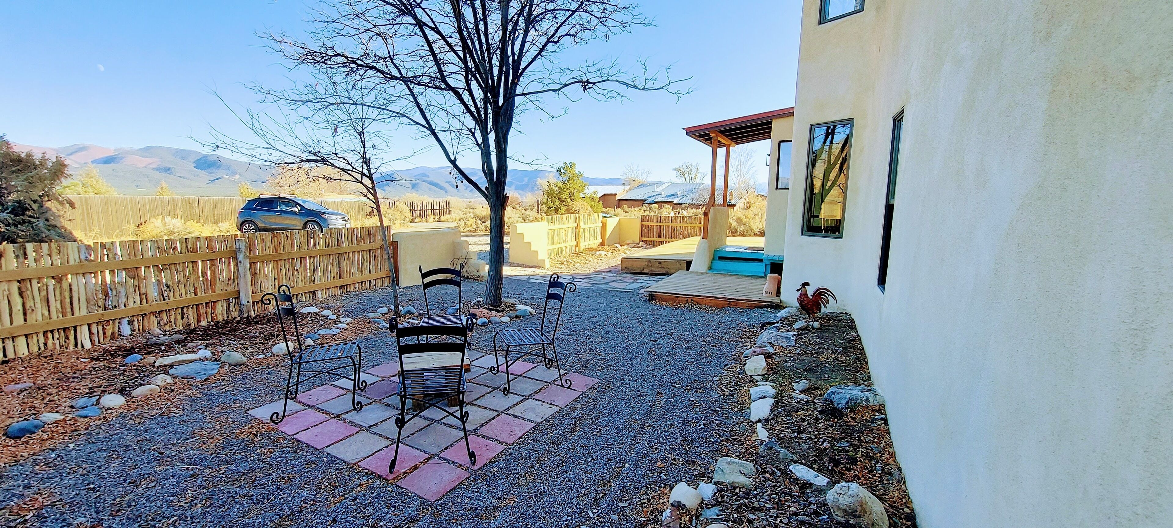 Ein Garten mit Kiesfläche, Holzlattenzaun, einer Metallbank und einem Patio-Tisch.