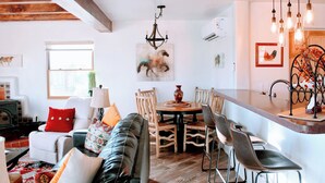 A cozy living room with a sofa, a dining table with chairs, a fireplace, and a kitchen area with a bar. - Entire home with privacy and views 10 mins to town 25mins to ski area  (El Prado)