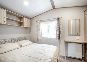 Une chambre à coucher avec un lit, une armoire, un radiateur et une fenêtre avec des rideaux.