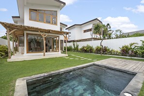 A modern two-story house with a swimming pool, a covered patio, and a well-maintained lawn.