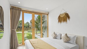 Ein Schlafzimmer mit einem großen Bett, Blick auf einen Garten durch Glastüren und einem an der Wand befestigten Dekorationsgegenstand.